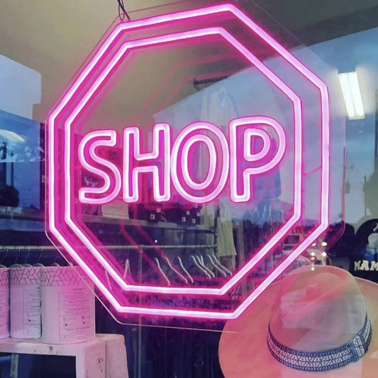 Custom LED neon pink lighted shop stop sign in boutique store window.