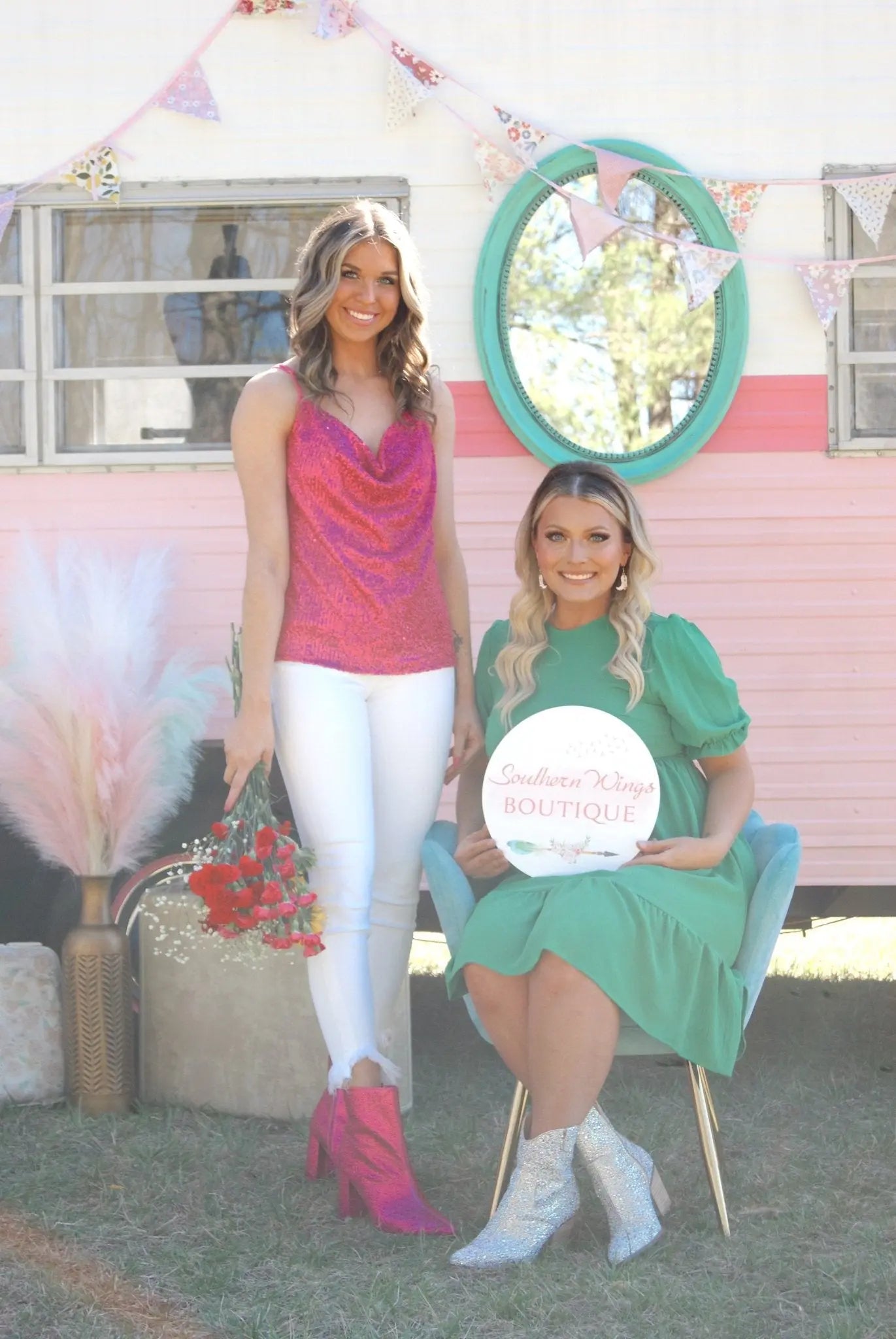 Two female business owners in front of their mobile boutique holding a custom business logo sign.