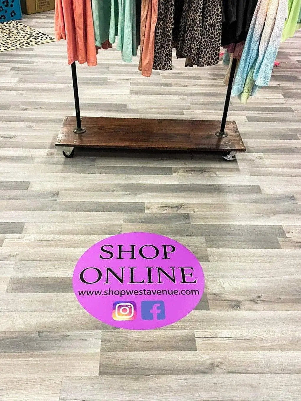 Custom floor decal in boutique shop pink with social media and website Facebook Instagram with clothing rack sales floor