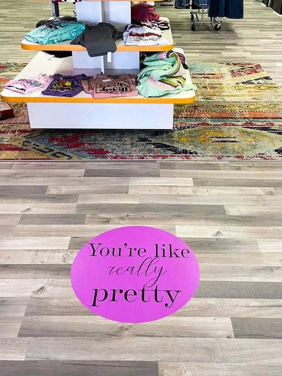 Custom floor decal in boutique shop pink you're like really pretty in front of clothing display sales floor
