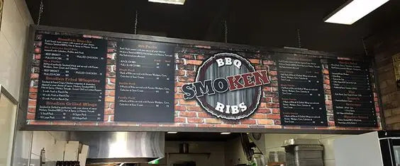 Custom menu boards with a logo for a restaurant suspended from the ceiling.