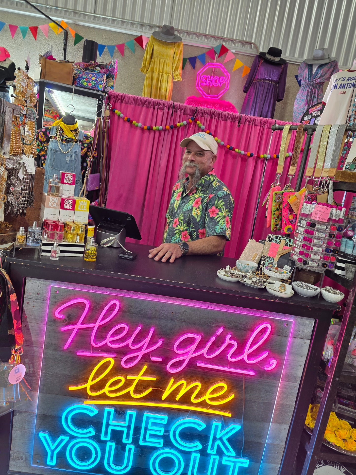 Neon lighted checkout sign in colorful boutique store with shop sign in background
