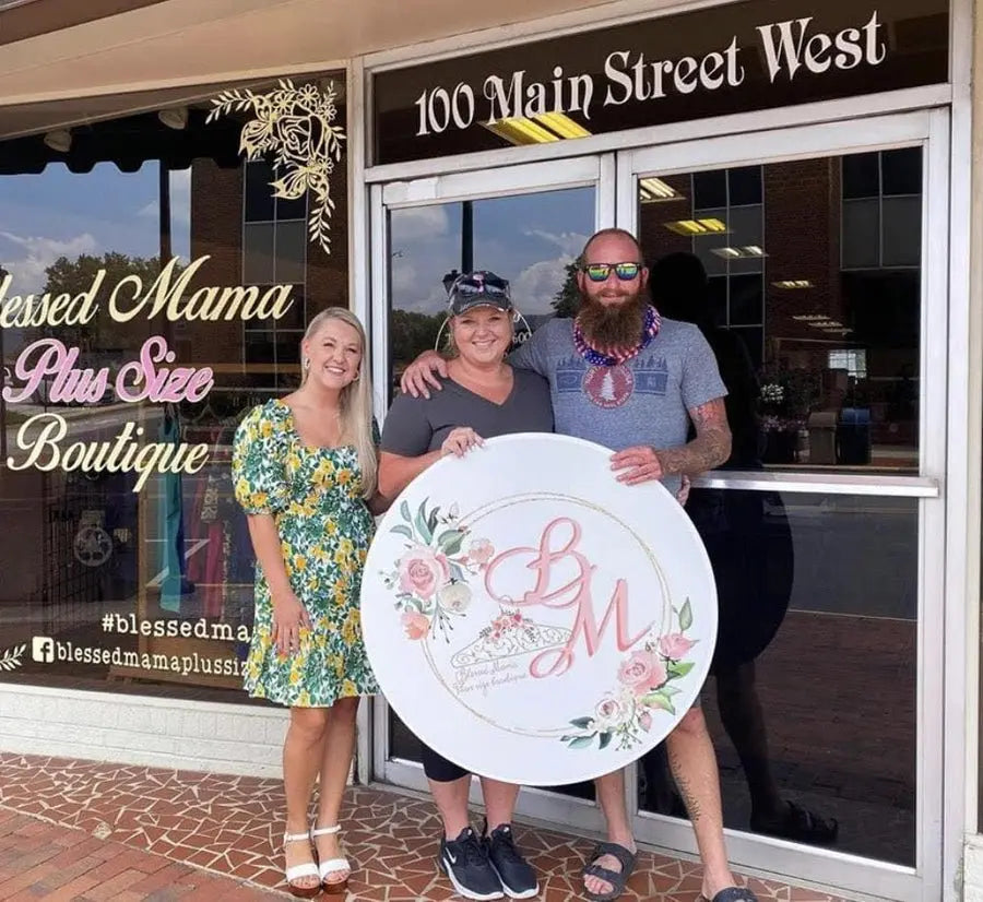 Happy business owners pose in storefront with their new custom business logo sign.