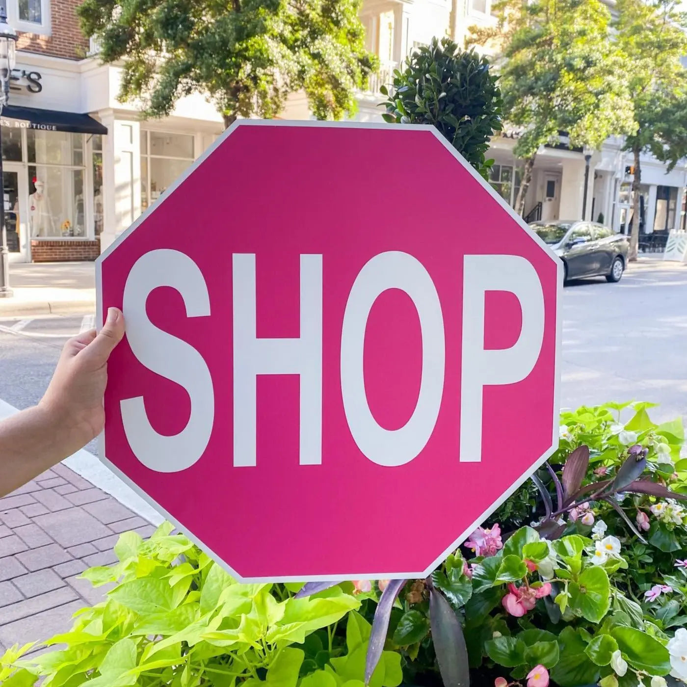Pink shop stop sign being displayed near shops.