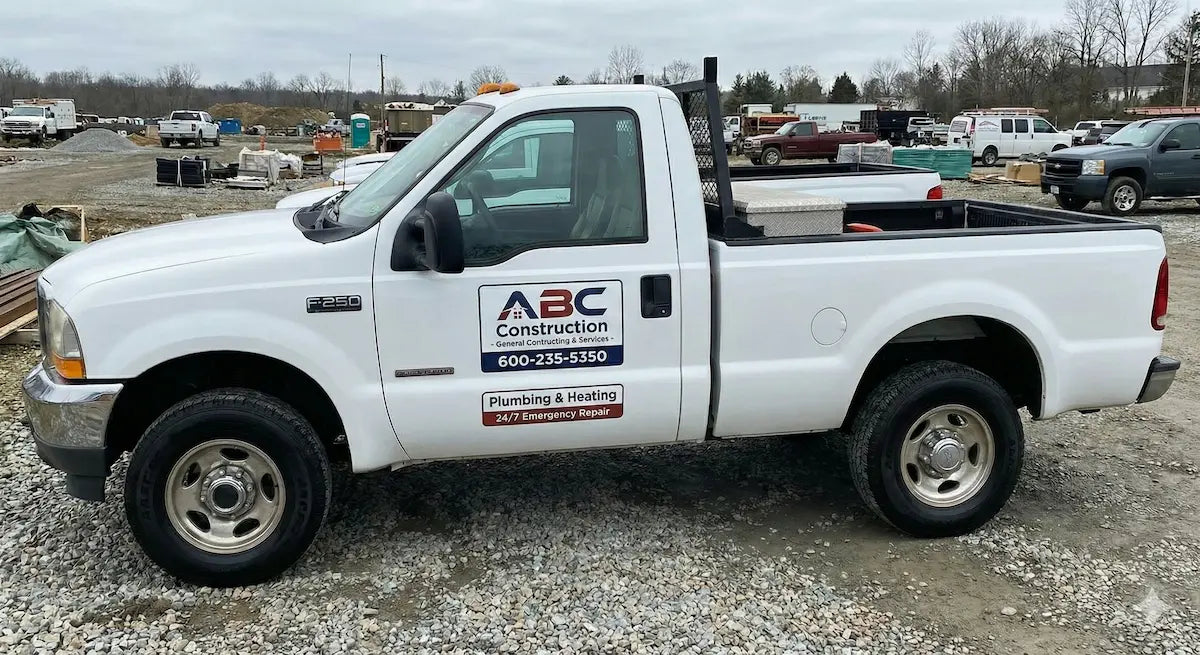 White pickup truck with vehicle magnet signs of ABC Construction logo on a construction site